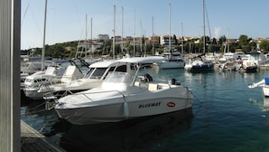 A marina with several boats docked, a clear sky, and buildings in the background. - Ida Pjescana (Medulin)
