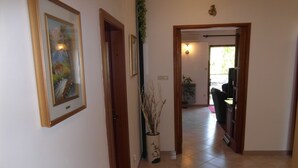 A hallway with a door leading to a room with a television and a plant. - Ida Pjescana (Medulin)
