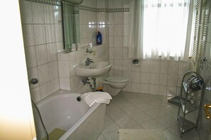 A bathroom with a bathtub, sink, and toilet. - Villa Viktoria (Loddin)