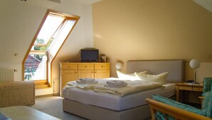 Ein Schlafzimmer mit einem Bett, einer Holzkommode, einem Sessel, einem Schreibtisch und einem Fenster.