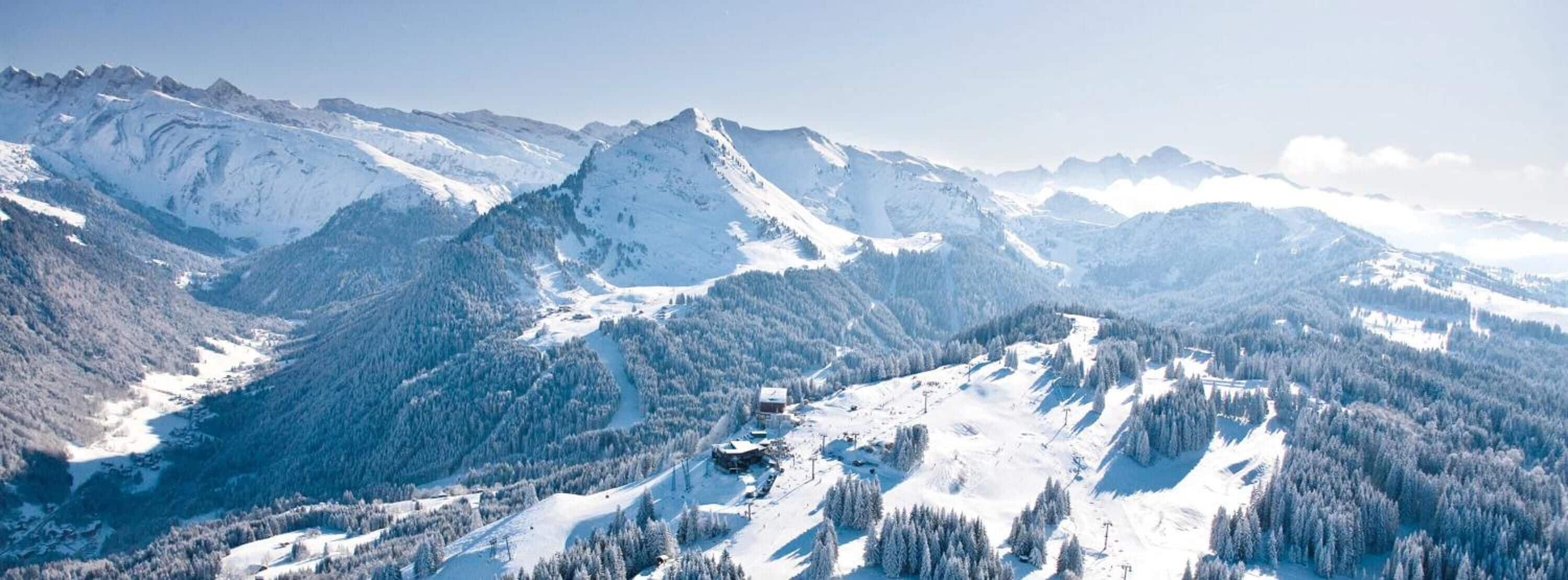 A mountainous landscape with snow-covered peaks and a small lodge in the valley.