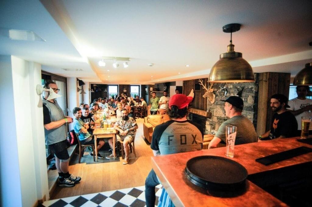 A group of people in a modern interior with a bar area, wooden flooring, and a stone wall.
