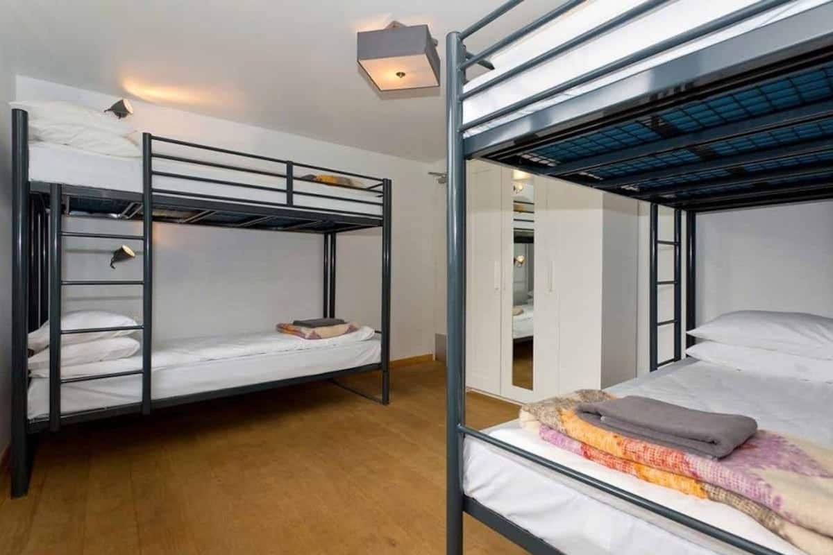 A dormitory room with bunk beds, a small desk, and a wardrobe.