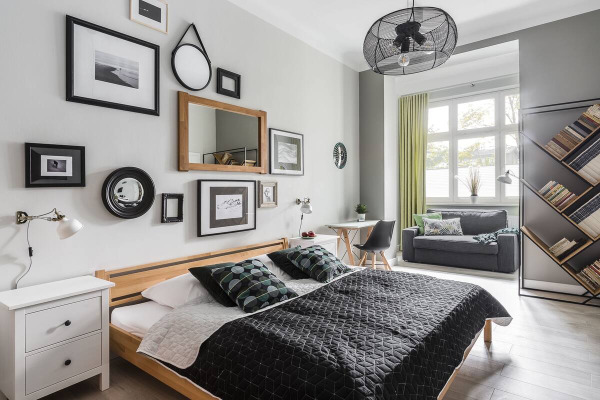 A modern bedroom with a large bed, bedside tables, a desk, and a bookshelf.