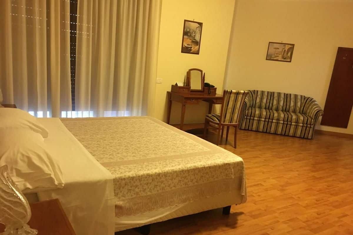 A room with a bed, a small table, a chair, and a sofa.