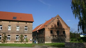 A historic building with a red-tiled roof and brick walls, featuring a prominent entrance and a staircase leading to the upper floor. - Herberge am Jakobsweg (Weissenfels)