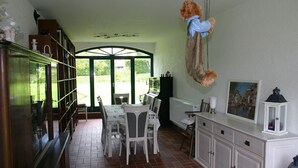 A dining area with a table and chairs, a cabinet with drawers, and a hanging teddy bear. - Herberge am Jakobsweg (Weissenfels)