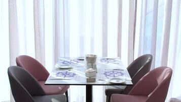 Une table à manger dressée pour quatre personnes, avec une nappe ornée d’une étoile de David, entourée de chaises.