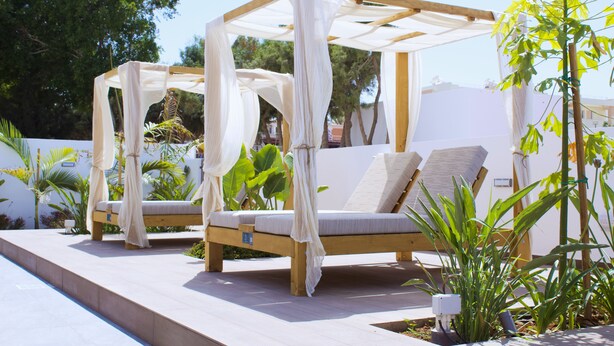 A wooden outdoor seating area with cushioned benches and a canopy structure. - Kapetanios Bay Hotel Protaras (Paralimni)