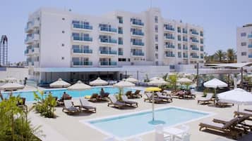 Un hotel con piscina, tumbonas y sombrillas.