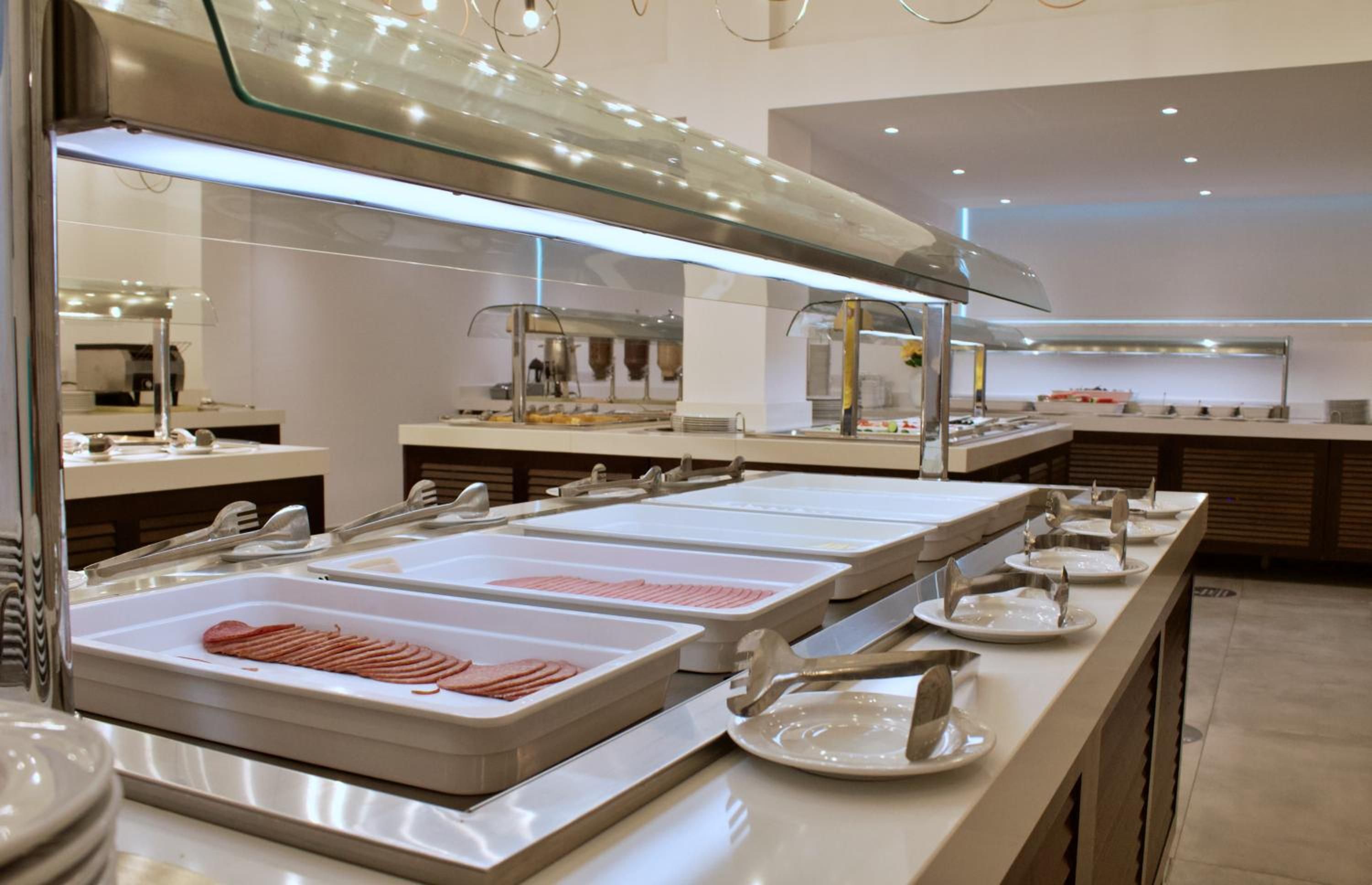 A buffet setup with multiple serving stations, each equipped with a tray of sliced meats and a set of utensils.