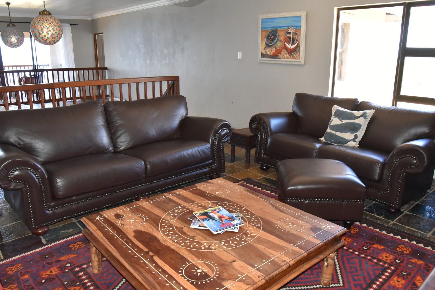 A living room with two leather sofas, a coffee table, patterned rugs, and a painting on the wall.