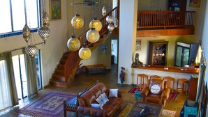 A spacious living area with a high ceiling, a staircase, and a dining area with a table set for six. - Villa Castellos (Jangamo)