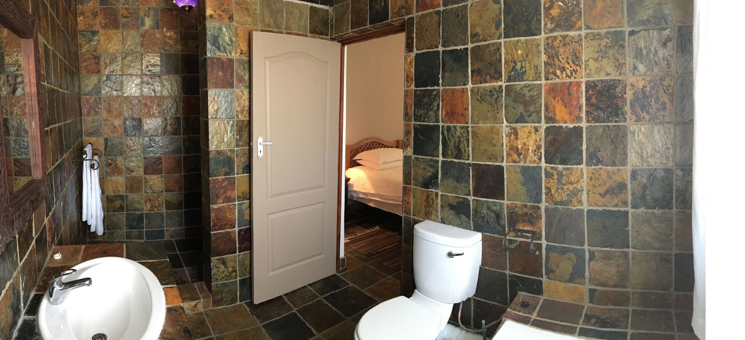 Un baño con lavamanos blanco, inodoro y zona de ducha.