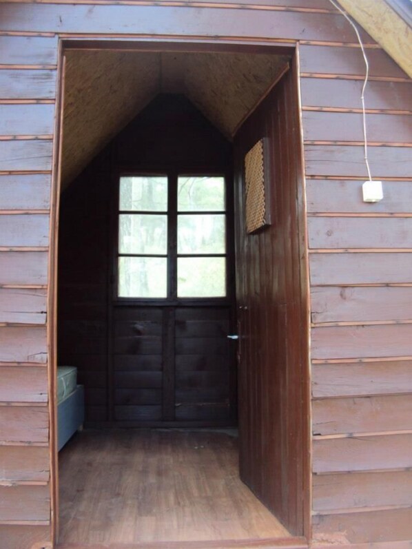 A wooden cabin with a large window and a door.