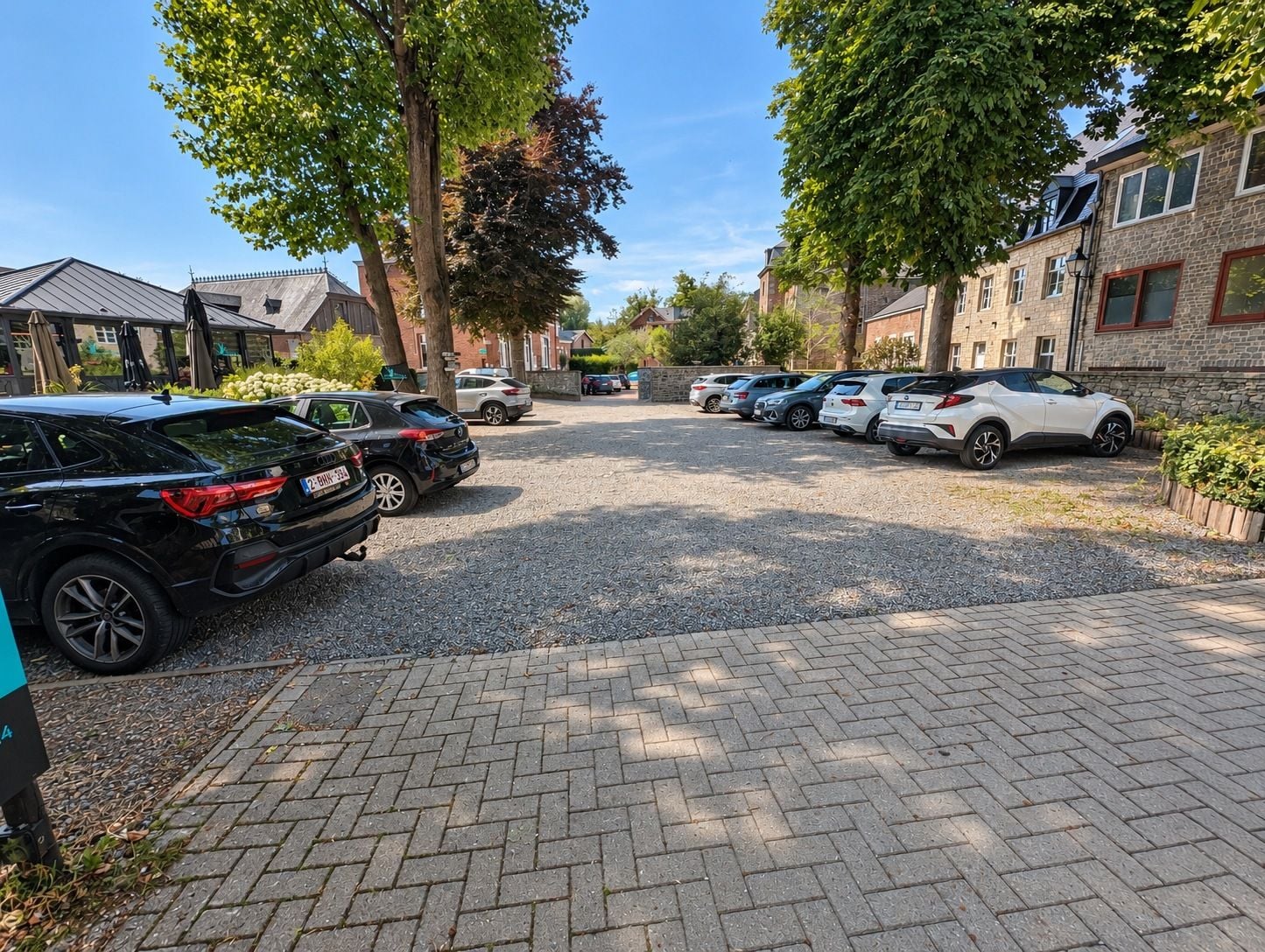 A parking area with multiple cars, a paved walkway, and residential buildings with brick facades.
