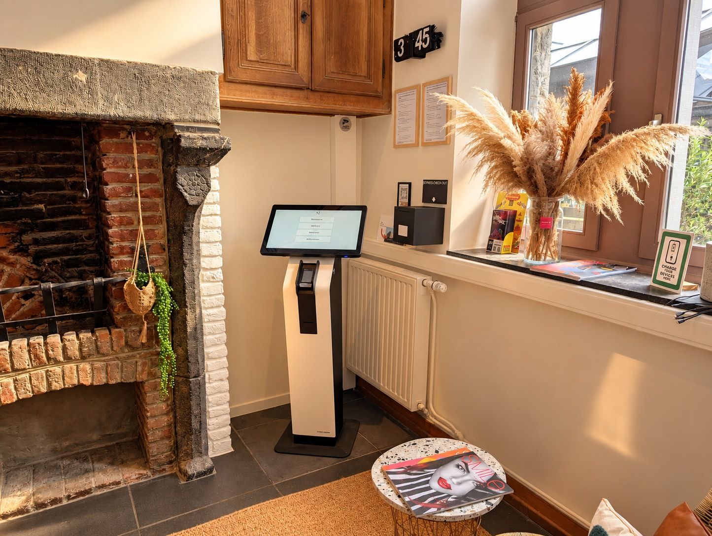 Een modern interieur met een open haard, een digitaal kiosk en een raam met uitzicht.