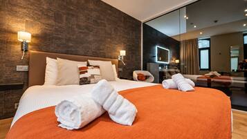Habitación de hotel moderna con una cama grande, dos lámparas de noche, un espejo y vistas a la ciudad.