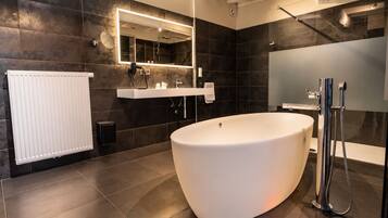 A modern bathroom with a freestanding bathtub, a large mirror, and a shower area.