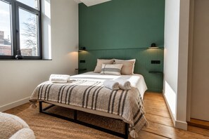 Une chambre à coucher avec un lit, des oreillers, une couverture et une table de chevet.