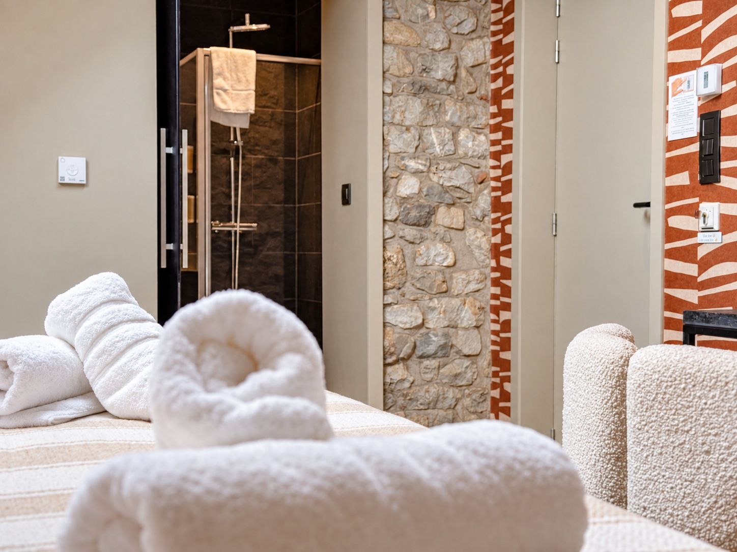 Ein Hotelzimmer mit Bett, Dusche und Steinwand.