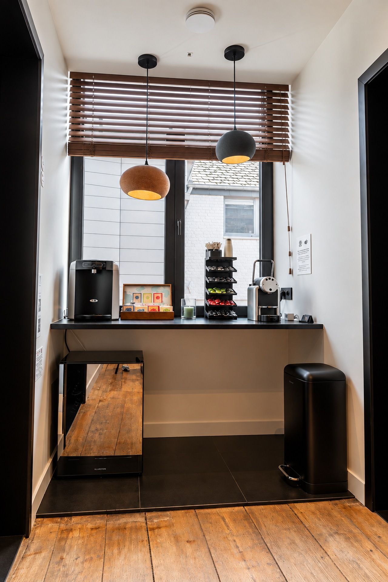 A modern kitchen with a built-in coffee machine, a kettle, and a coffee grinder on the counter.