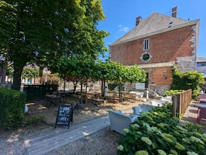 A courtyard with outdoor seating, a brick building, and a signboard. - Hôtel Le Manoir (Marche-en-Famenne)