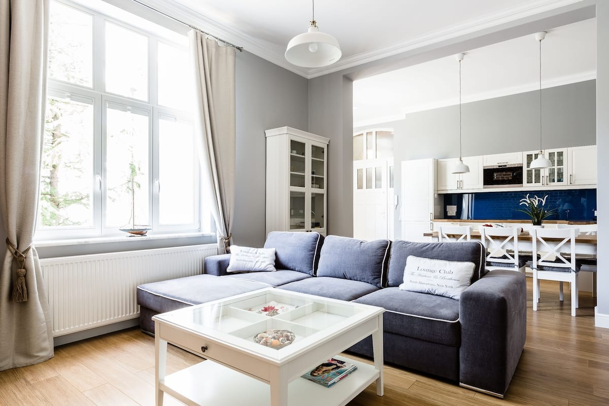 A modern living room with a grey sofa, a glass coffee table, and a white cabinet.