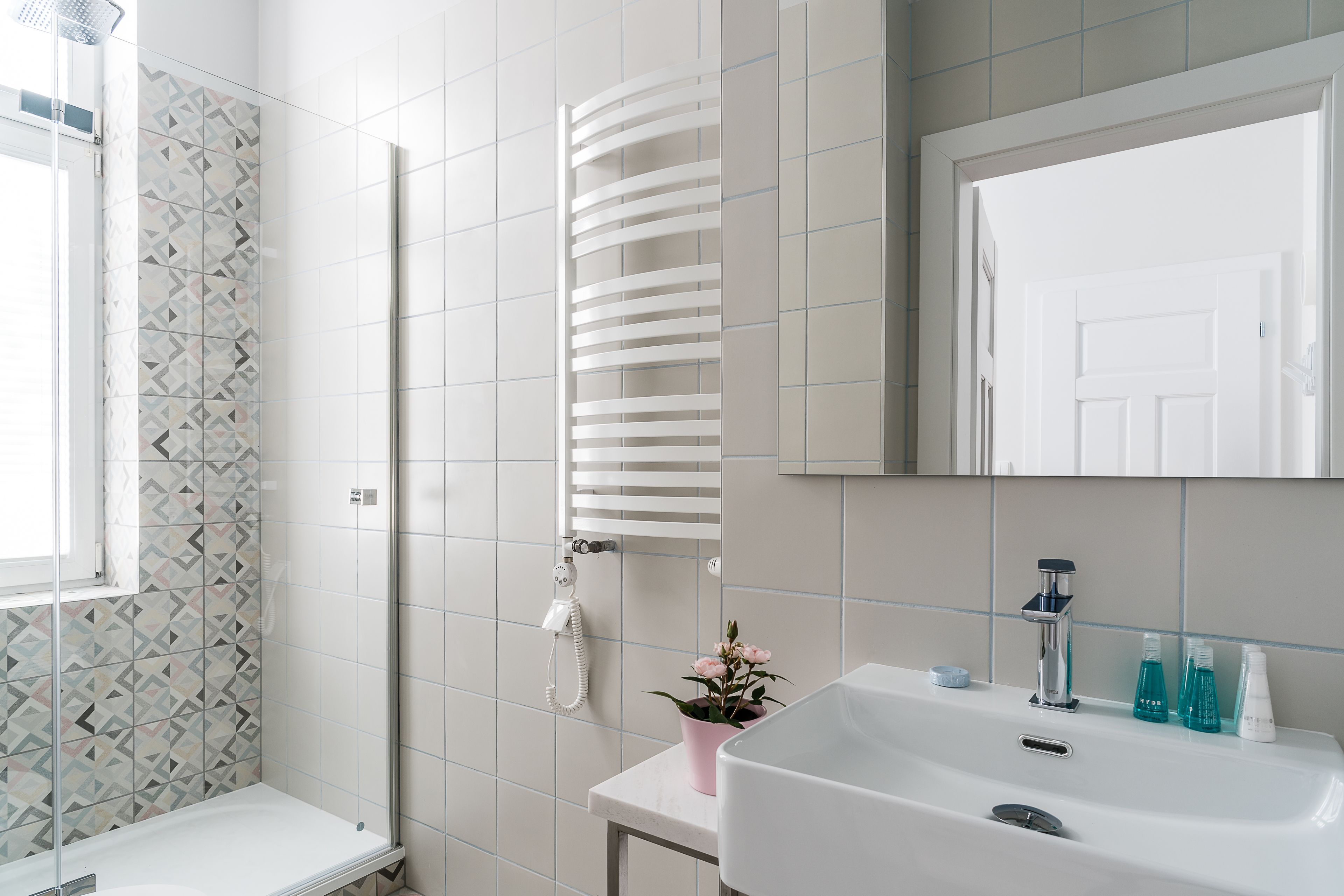 A bathroom with a shower, a sink with toiletries, and a mirror.
