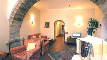 Una stanza con un arco in pietra, un divano, un tavolino e una televisione.