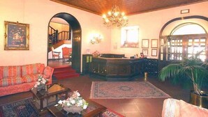 Un vestíbulo con sofá, mesa de centro, candelabro y recepción.