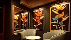 A room with two armchairs, a small round table, and three framed floral paintings on the wall. - The Bedford Balham (London)