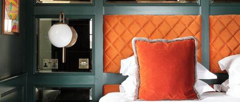 Una habitación de hotel con cama, mesita de noche, espejo y cómoda.