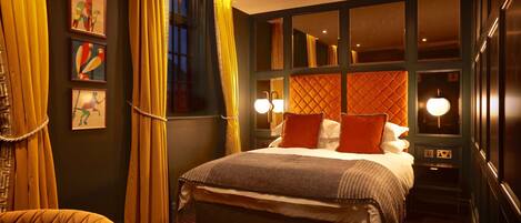 A hotel room with a large bed, two bedside lamps, a window with curtains, and artwork on the wall.