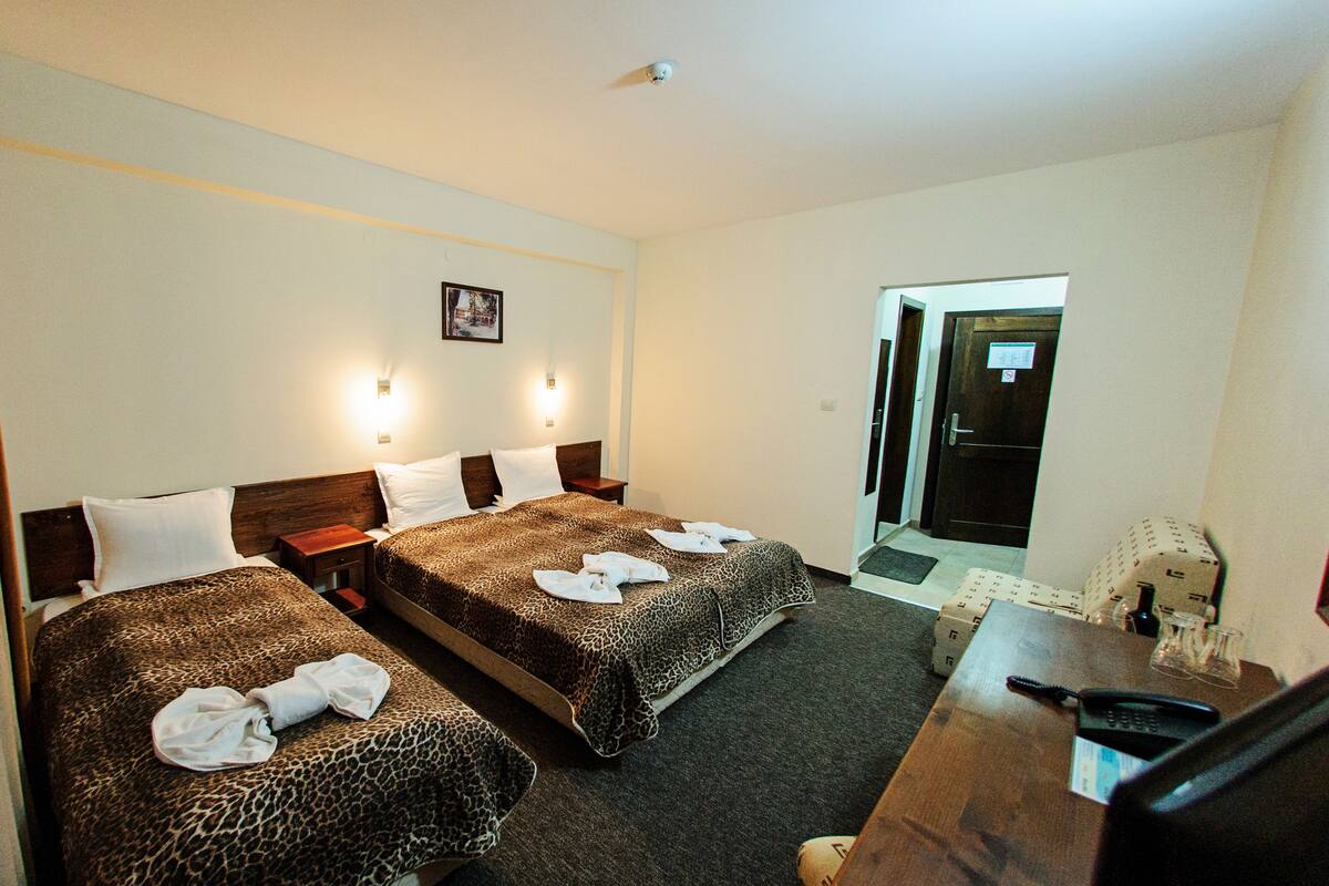 A hotel room with two beds, a desk with a telephone, and a door leading to the hallway.