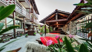 A courtyard with stone walls, wooden benches, and potted plants. - Hotel Dumanov (Bansko)