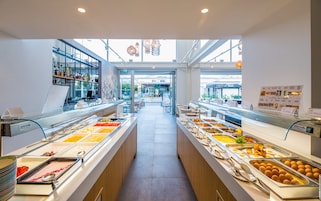 A buffet area with various food options, a bar with beverages, and a view of the outdoor seating area.