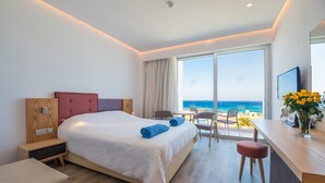 A modern hotel room with a large bed, a desk, and a view of the ocean. - Protaras Plaza Hotel (Paralimni)
