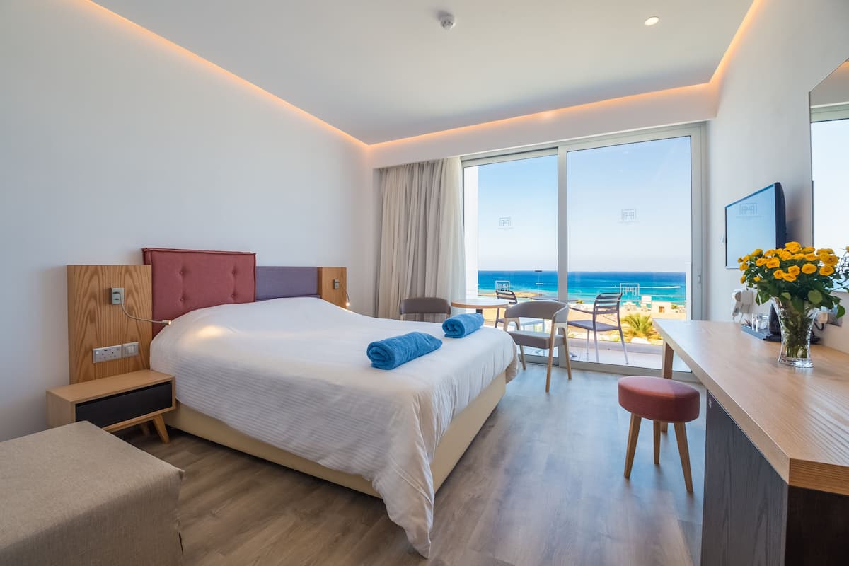 Una habitación de hotel moderna con una cama grande, un escritorio y vistas al océano.