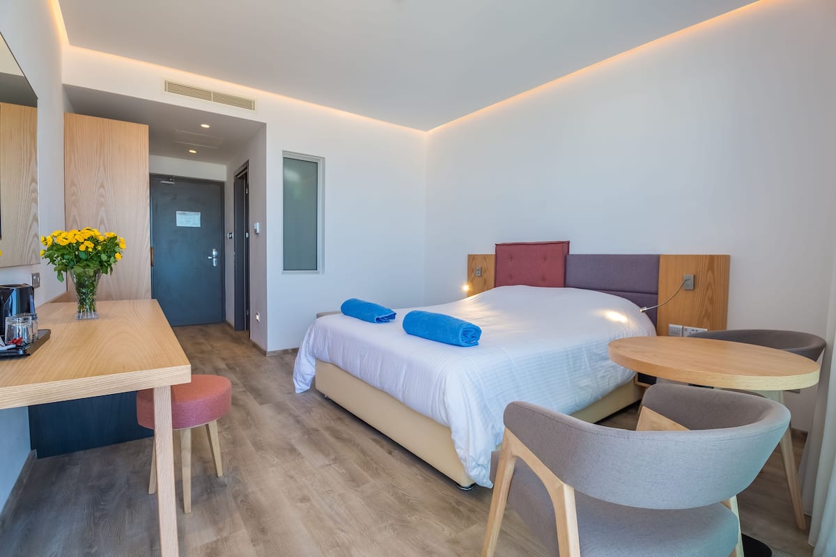Una habitación de hotel moderna con una cama, un escritorio, una silla y una mesita.