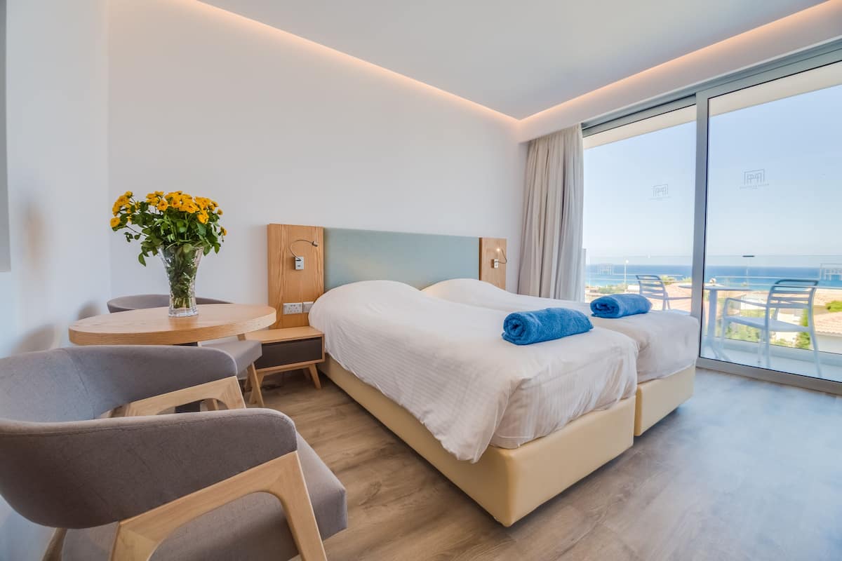 Habitación de hotel moderna con una cama grande, un escritorio pequeño, una silla y vistas al mar.