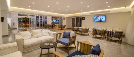 A spacious lobby with a seating area, a bar, and a television screen.