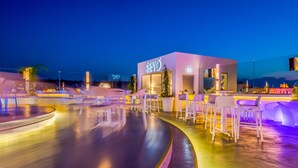 A modern bar area with a neon sign, bar stools, and a pool.