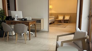 Ein modernes Zimmer mit Schreibtisch, Computer und Sitzecke.