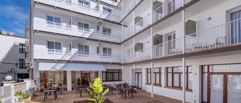 A multi-story hotel with outdoor seating, balconies, and a central courtyard.