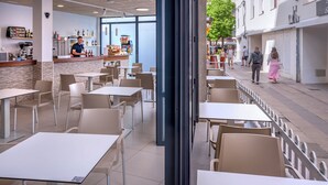 Ein Café im Innenbereich mit Tischen, Stühlen und einer Bar, mit Blick auf die Straße.