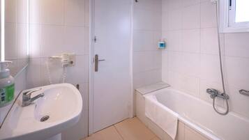 A bathroom with a white sink, a bathtub, and a shower.