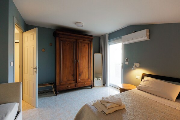 Habitación de hotel con cama, armario, espejo, equipo de aire acondicionado y lámpara de noche.