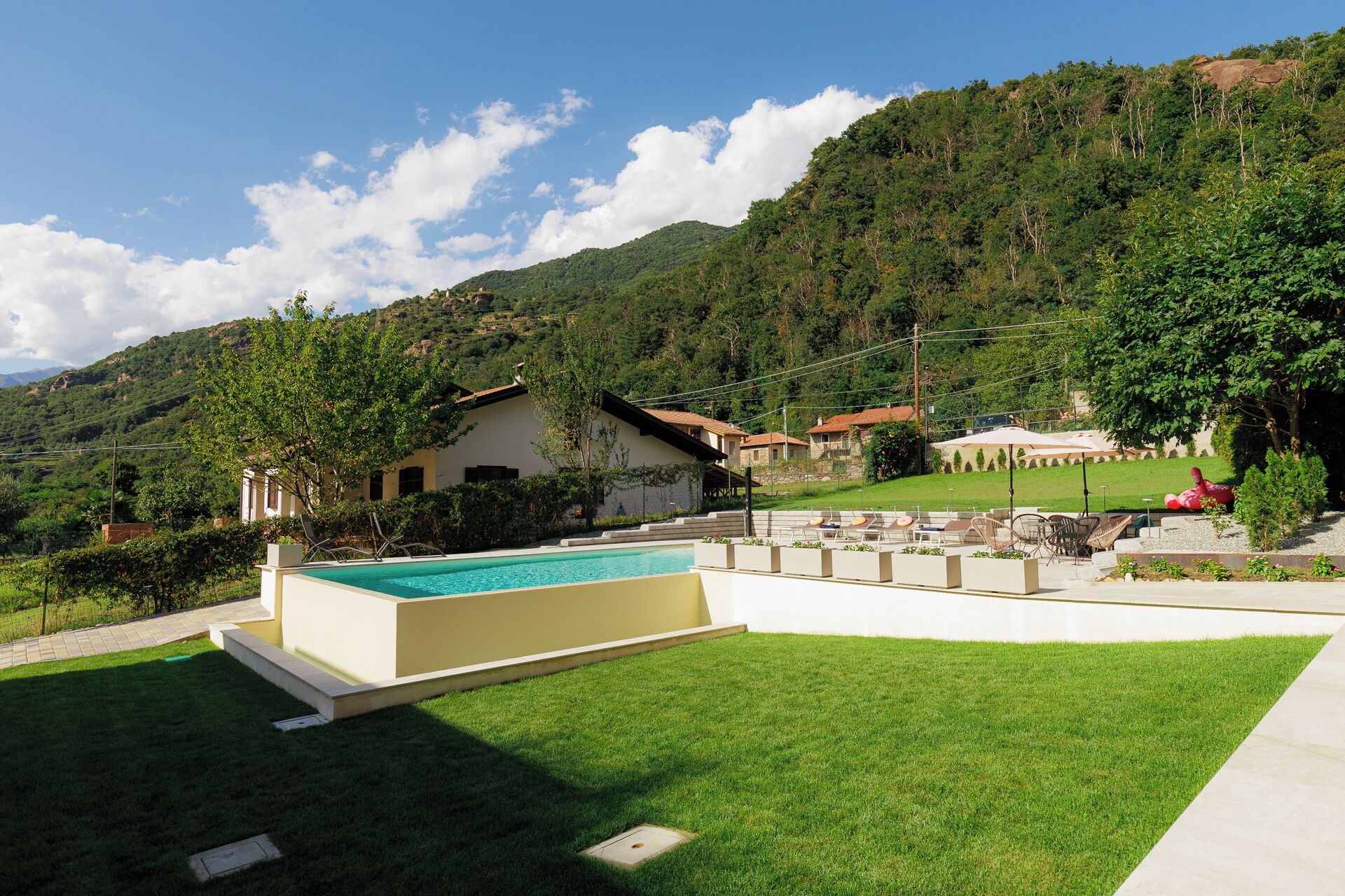 Zona de piscina con vistas despejadas del paisaje circundante, incluyendo una casa y colinas al fondo.