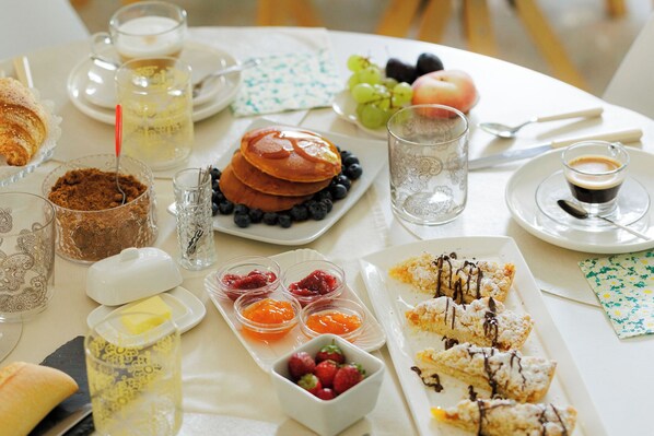 Una mesa de desayuno con tortitas, fruta y café.